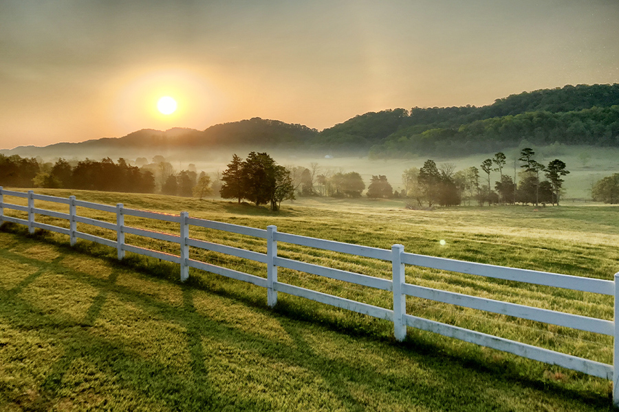 Pasture, Rangeland, Forage Insurance - Sunrise Over Pasture and a White Fence with Trees and Hills in the Background