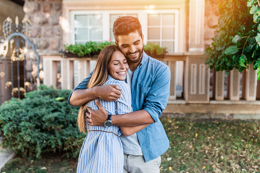 Personal Insurance - Portrait of a Happy Young Couple Hugging Each Other in Front of Their New Home
